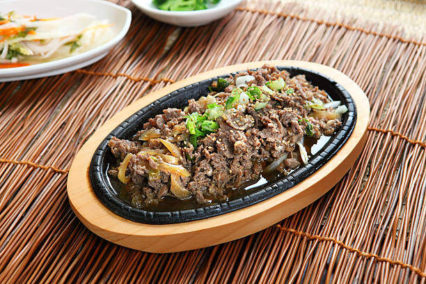 Bulgogi on a wooden platter on a straw table Korean Style BBQ, Sliced Beef Marinated with Soy sauce banchan stock pictures, royalty-free photos & images