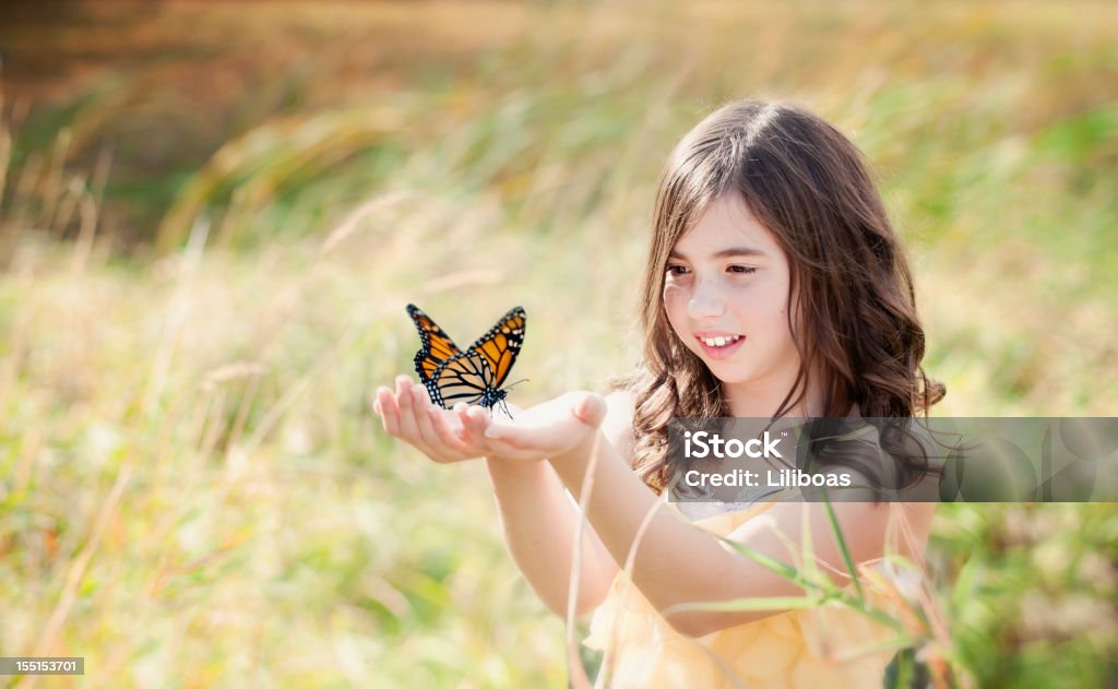 Fille dans le champ tenant un papillon monarque - Photo de Papillon libre de droits
