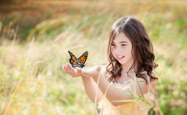 istock Girl in Field Holding a Monarch Butterfly 155153701