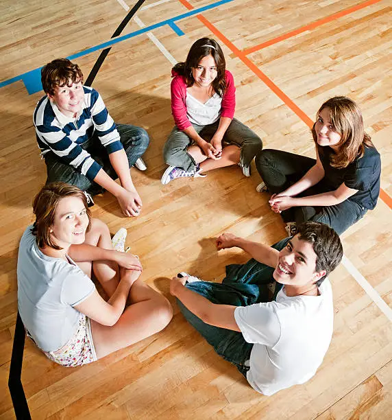 Photo of Five students sitting in a circle in a gym