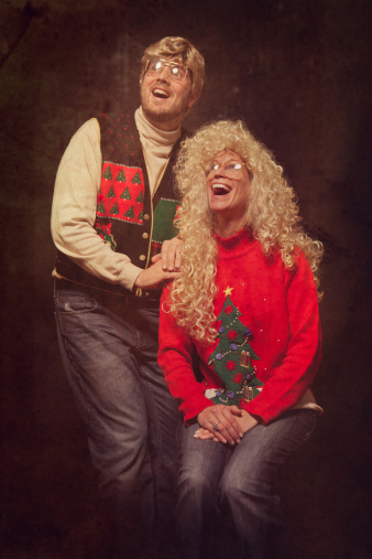 A man and woman from the 1980s with glasses, highlighted hair, and classy Christmas sweaters poses for a picture at a classic photo studio.  Intentional 80's style kitsch post processing emulation.  Vertical.