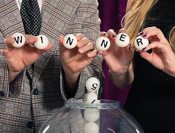 A Retro color processed lottery drawing show and assistant host holding balls spelling WINNER. Photographed in studio with a purpose built set and props.