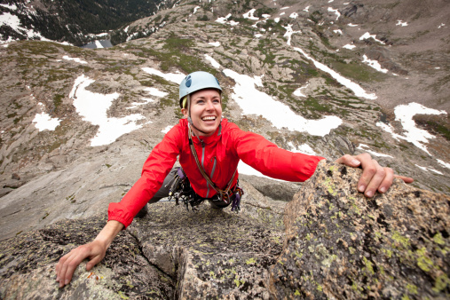Smiling young woman leading a climbing route in Colorado Spear Head (North Ridge) in Rocky Mountain National Park, Colorado.