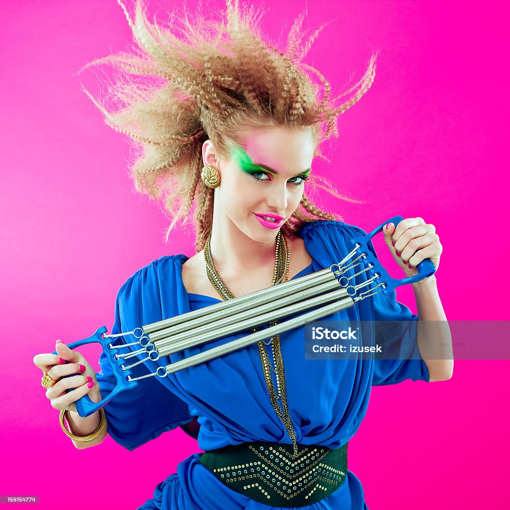 80s style woman with expander Portrait of 1980s style sensual young woman holding modern chest expaner in her hands, smirking at the camera. Exercising Stock Photo