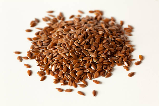 brown flax seeds A close up of a pile of dries flax seeds on a white background. flax seed stock pictures, royalty-free photos & images