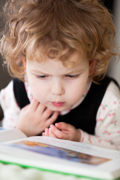 istock Little girl reading a book 155156652
