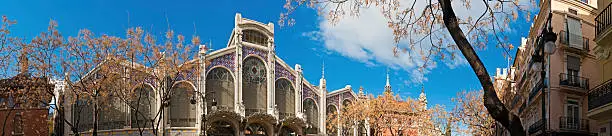 Panoramic view across the Plaza del Mercado past the Lonja de la Seda to the historic Art Nouveau Mercado Central housing a thousand market stalls in the old town of Valencia, Spain. ProPhoto RGB profile for maximum color fidelity and gamut.