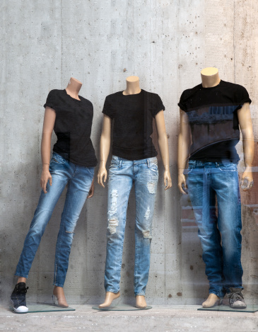 Shop window with three mannequins wearing blue jeans and black t-shirts