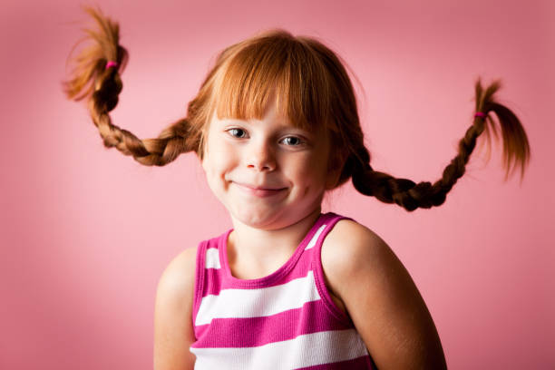 istock Red-Haired Girl with Upward Braids Smiling on Pink Background 155157032