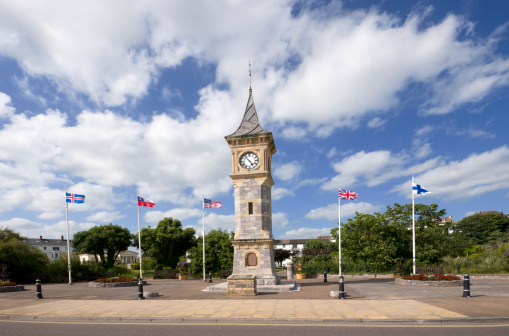 Taken by the sea front is this clock tower with flags blowing in the wind