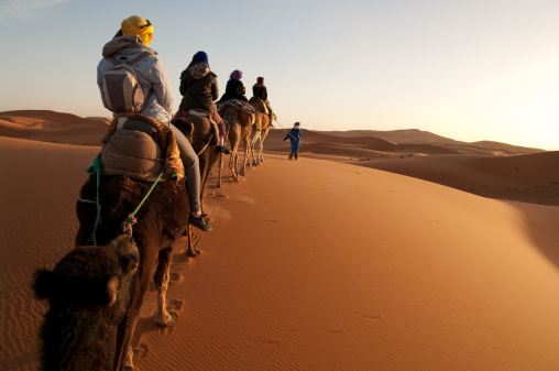 Los turistas en tren de camellos en Sahara led de guía photo