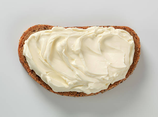 Slice of bread, spread with cheese against white background