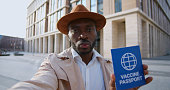 African male tourist with vaccination passport looking at camera and talking outdoors