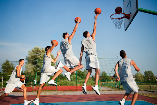 Side view of young male basketbal player scoring, multiple image