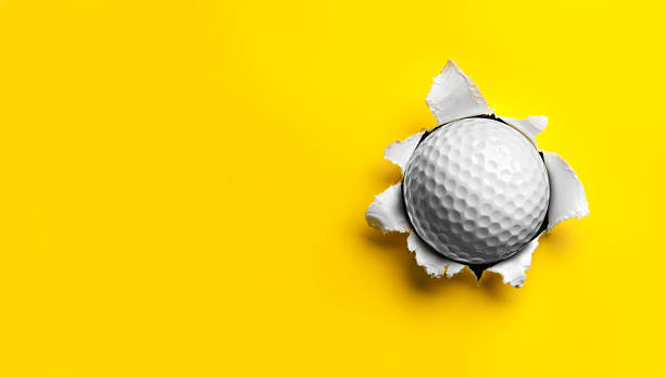 Golf Ball stuck in Yellow Paper stock photo