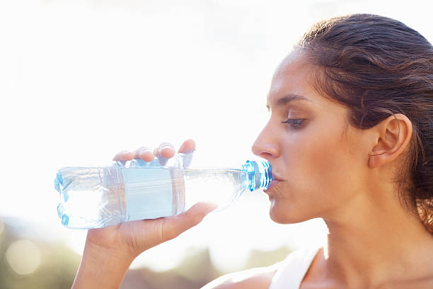 istock Young woman drinking bottled water 155158212