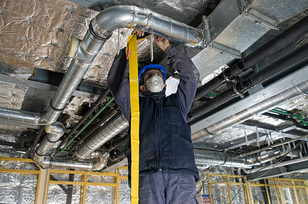 Worker wrapping an HVAC air duct with foil tape Worker Wrapping an HVAC Air Duct with Foil Tape Air Exchanger stock pictures, royalty-free photos & images