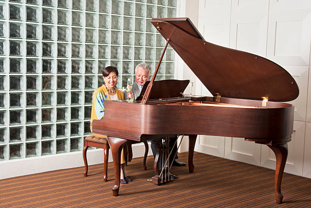 una pareja senior asiática tocando el piano de cola - pianist grand piano piano playing fotografías e imágenes de stock