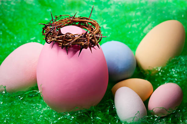 Grouping of Easter eggs--one topped by a crown of thorns; others fallen around it--with Easter grass in the background.