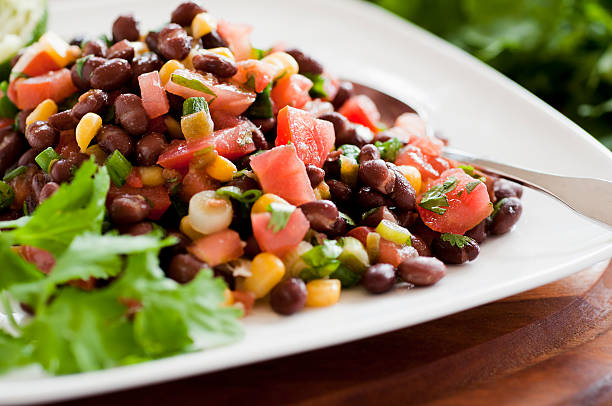 Black bean salad on white plate siting horizontally on table stock photo