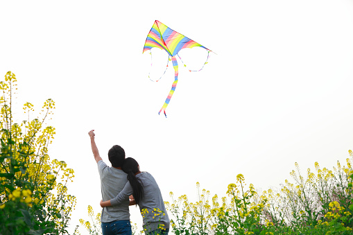 young couple flying kite in the spring field .