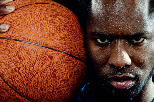 A young African American basketball player holding a basketball. Shallow focus on right eye.  