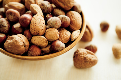 Many mixed nuts, walnuts, cashews, almonds, macadamia nuts, pistachios, peanuts in wooden bowl