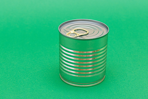 Unopened Tin Can with Blank Edge on Green Background. Canned Food. Aluminum Can for Safe and Long Term Storage of Food. Steel Sealed Food Storage Container