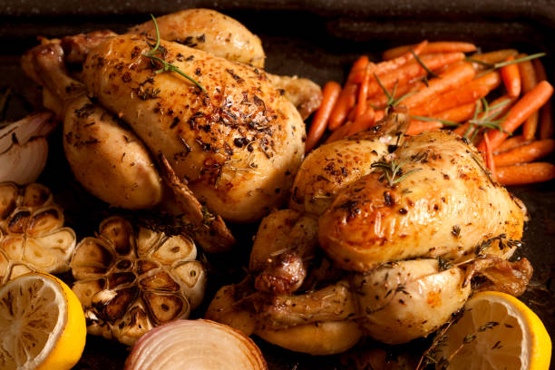 Rosemary roasted chickens with carrots, garlic, and onions on a tray.