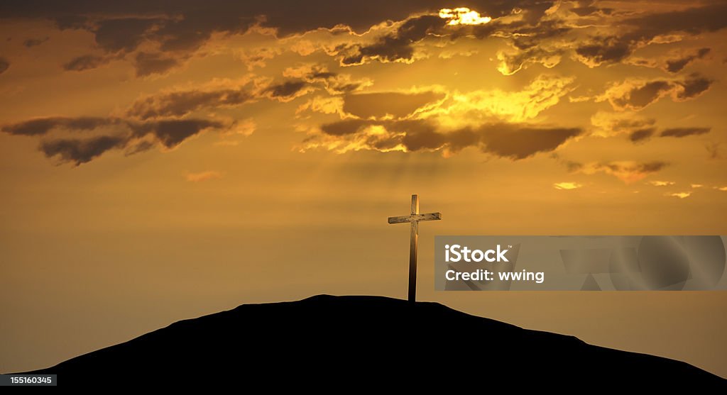Christian Cross atop a Hill Against a Morning Sunrise A gold colored cross under a rising Easter morning sun. Cross Shape Stock Photo