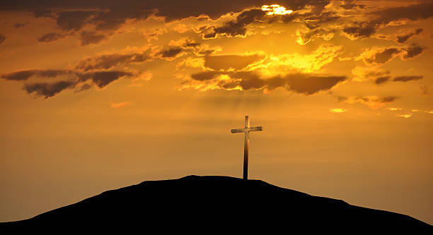 Christian Cross atop a Hill Against a Morning Sunrise stock photo
