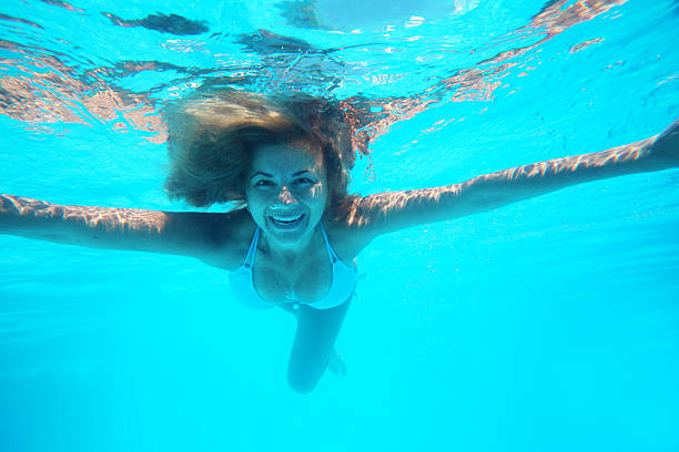 istock Cheerful woman under the water looks at camera 155160499