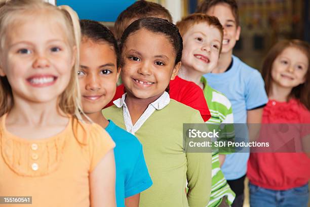Elemental Estudiantes Joven Sonriendo Mientras Espera En Línea Foto de stock y más banco de imágenes de Hacer cola