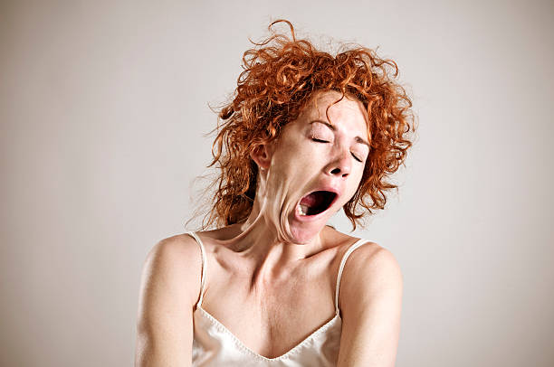 Yawning red haired woman in silk shirt