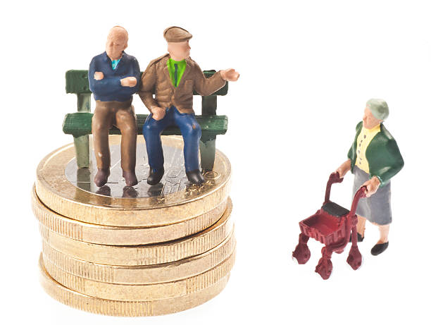 Senior figurines standing on stack of coins.