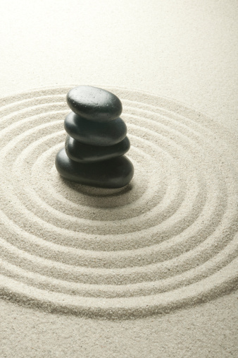 Balanced Black Pebbles in Sculpted Sand.