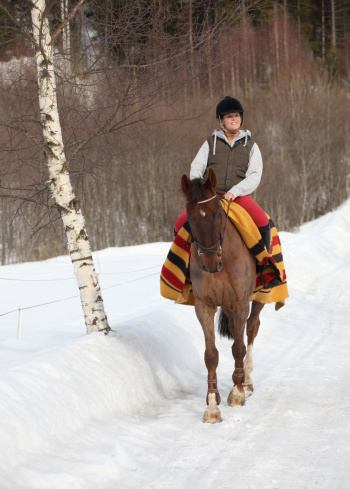 Young woman horseback riding in the snow, Oslo Norway