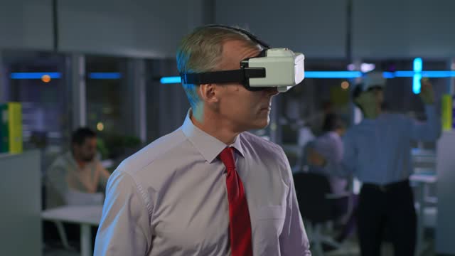 Mature businessman in virtual reality goggles in office