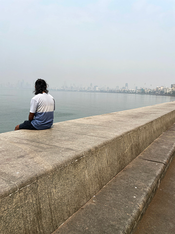 Stock photo showing close-up view of a manmade, sea defence of a concrete, seawall, which has been constructed to prevent flooding of the promenade of Marine Drive, Mumbai, India during high tide.