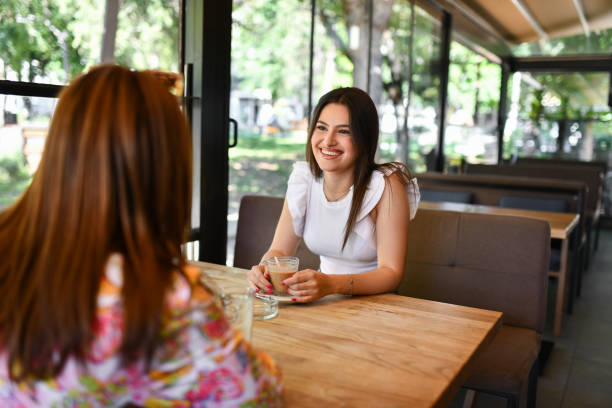 istock Smiling Female Enjoying Coffee Time And Conversation With Friend 1551716976
