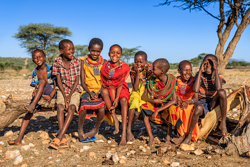 Group of happy African children from Samburu tribe sitting on tree trunk, Kenya, Africa. Samburu tribe is north-central Kenya, and they are related to  the Maasai.