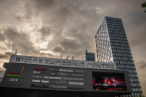 Picture of the main facade of usce Shopping center during a cloudy afternoon. Usce Tower is a 25-story mixed use skyscraper in the New Belgrade municipality of Belgrade, Serbia. It is currently the tallest building in Serbia. the glass building overlooks the confluence Danube and Sava rivers from the New Belgrade side, and is located near a Shopping center
