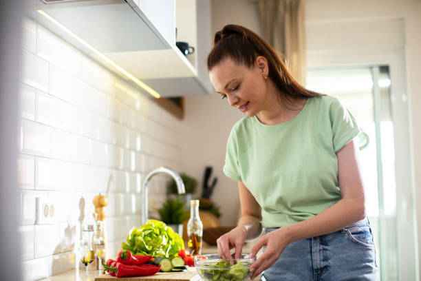 istock Young woman cutting and preparing vegetables in a kitchen at home 1551881301