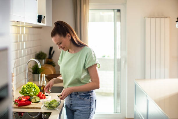 istock Young woman cutting and preparing vegetables in a kitchen at home 1551883897
