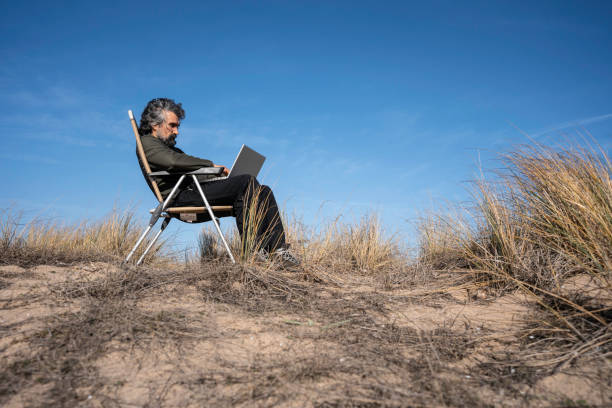 istock Man works on laptop while on vacation at the sea. copy space 1551922384