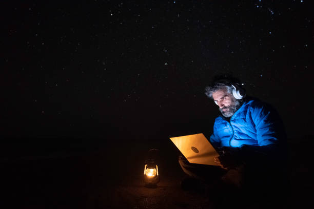istock People in nature. Man works at night on laptop at seaside. copy space 1551922394