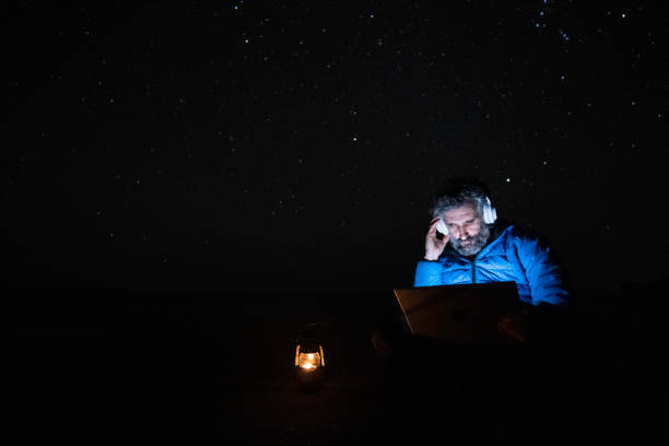istock People in nature. Man works at night on laptop at seaside. copy space 1551922395