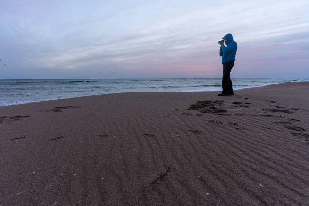 Man on snowy and windy beach looking at stormy sea