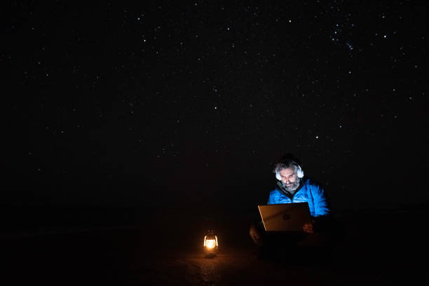 istock People in nature. Man works at night on laptop at seaside. copy space 1551922686