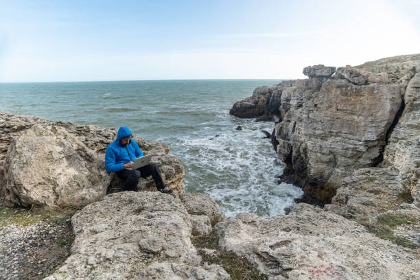 istock People and nature. Man works on laptop at seaside. copy space 1551922907